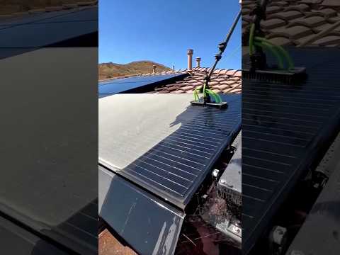 Automated cleaning brush washing rooftop solar panels to maintain peak energy efficiency